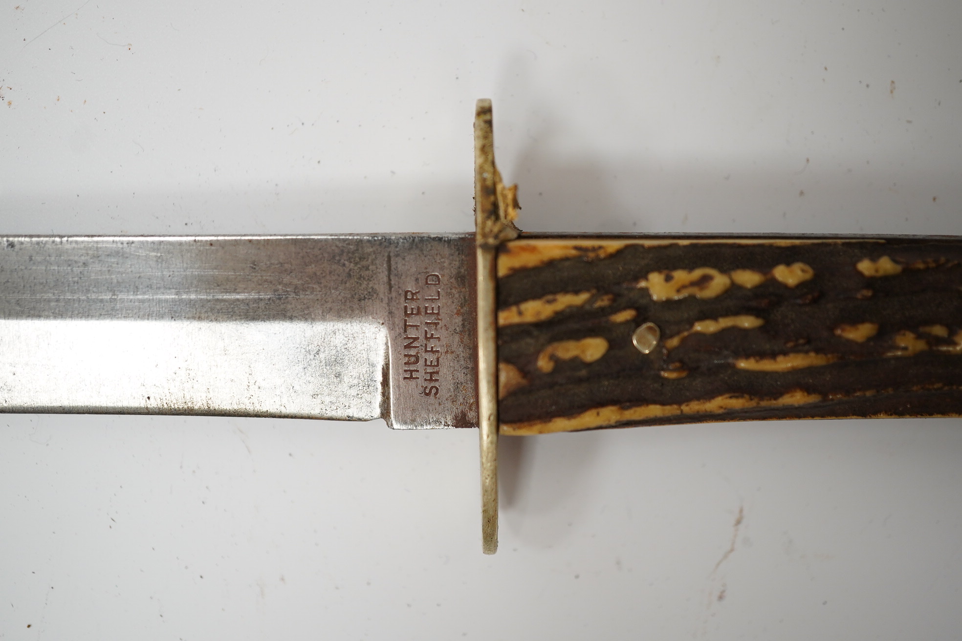 A Hunter of Sheffield, ‘Bugle Knife’ with horn grips, in its leather sheath, blade 15cm. Condition - fair